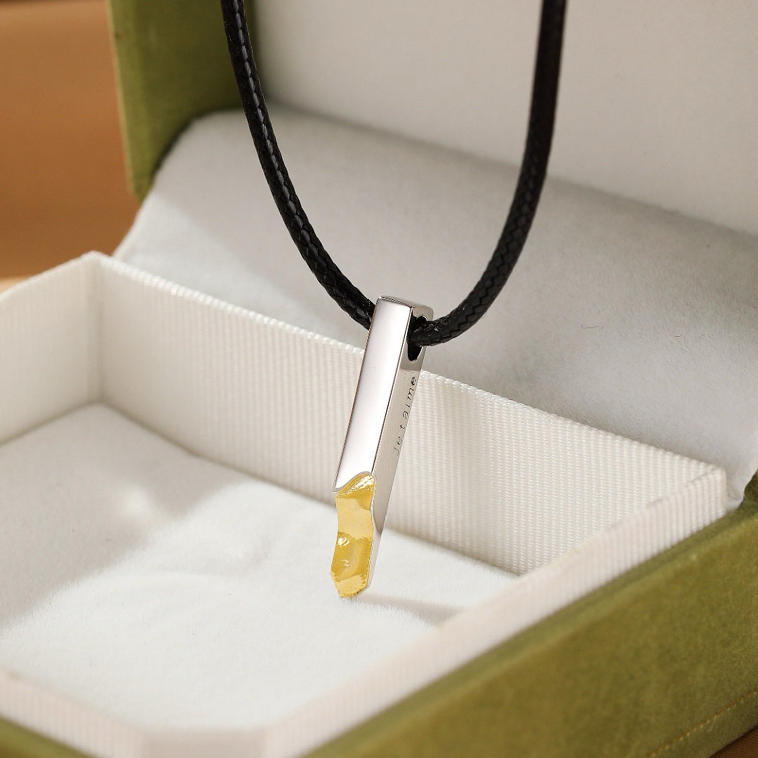 Collier de couple "Lignes d’Essence" en argent avec une pierre jaune brute, présenté dans une boîte verte ouverte.