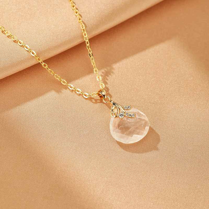 Collier plaqué or avec pendentif en cristal de roche facetté en forme de goutte, orné de motifs feuilles et de zircons.