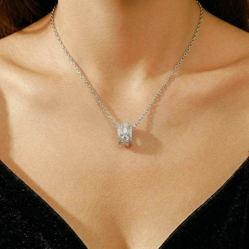Collier élégant en argent avec un pendentif cylindrique orné de cristaux scintillants, porté par une femme.