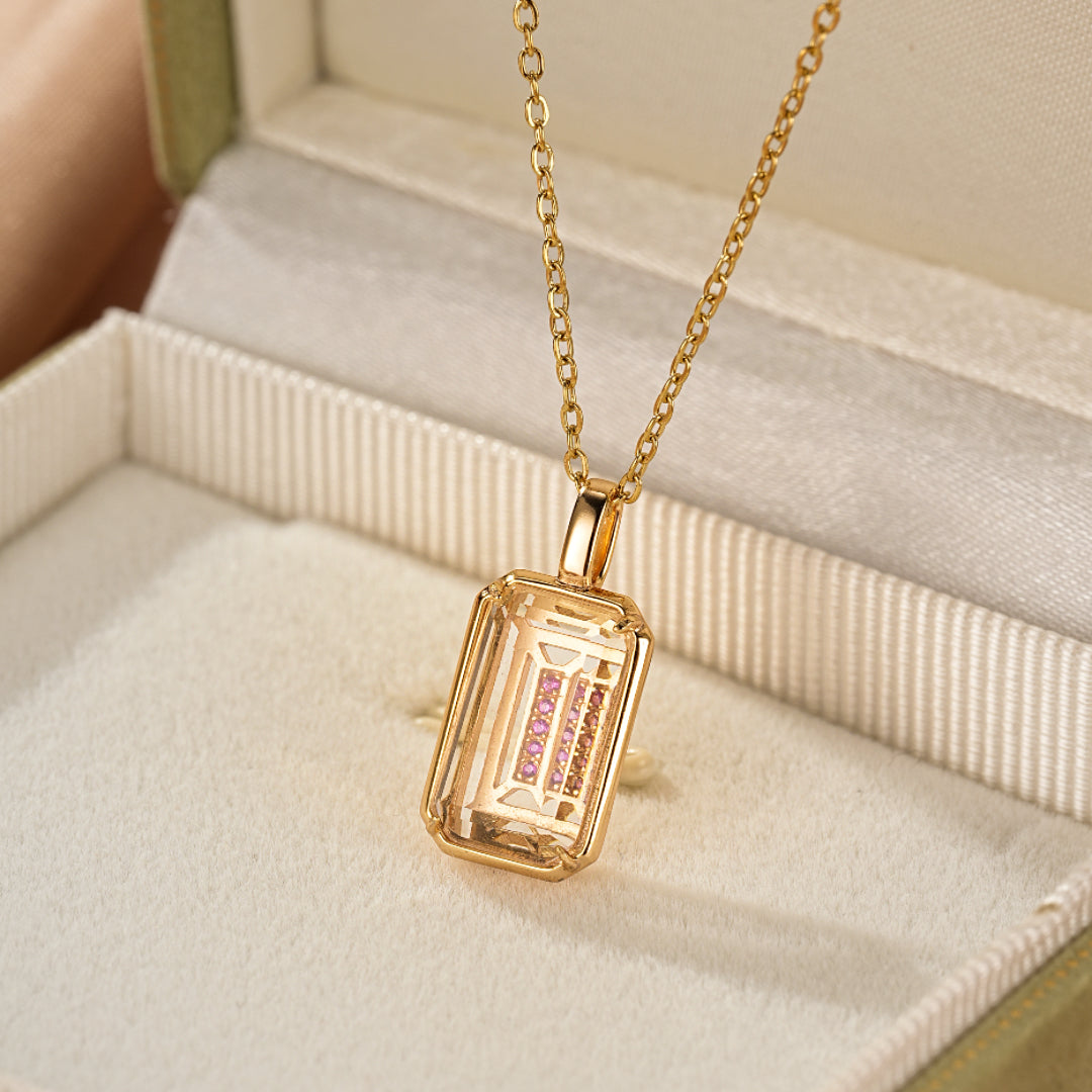 Collier avec un pendentif rectangulaire en Cristal de Roche transparent, serti d'une rangée de petites pierres roses, le tout monté sur une chaîne plaquée or 10K.