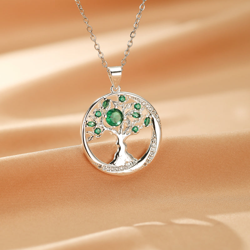 Collier Arbre Éternel en argent avec pendentif rond orné d'émeraudes vertes et de zircons cubiques scintillants.