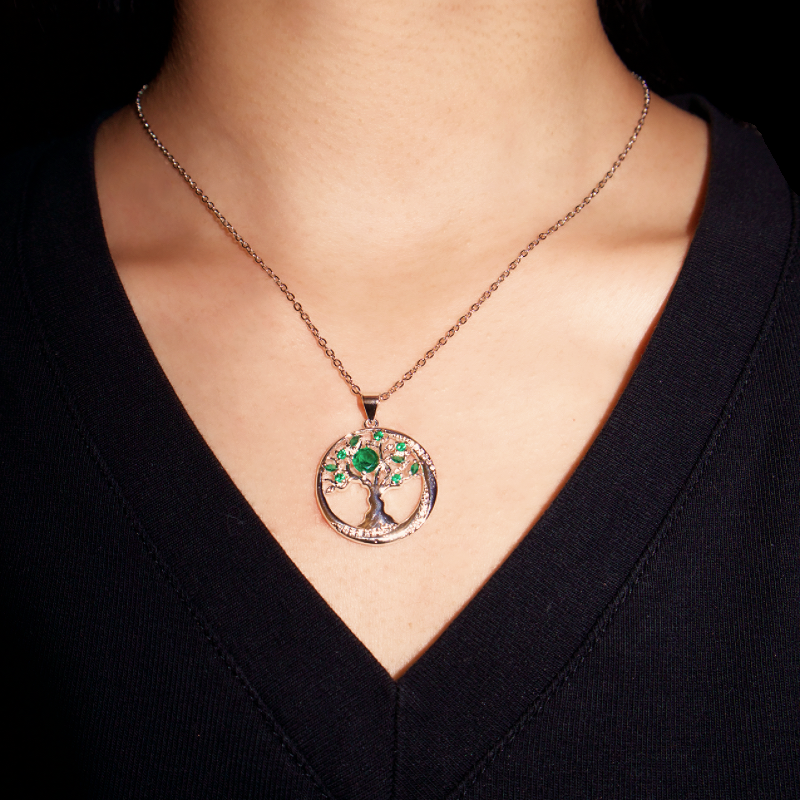 Collier Arbre Éternel avec pendentif arbre de vie serti d'émeraudes et de cristaux, porté sur une personne.