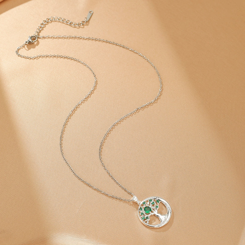 Collier en argent avec pendentif rond Arbre de Vie orné de pierres vertes émeraude et de cristaux brillants.