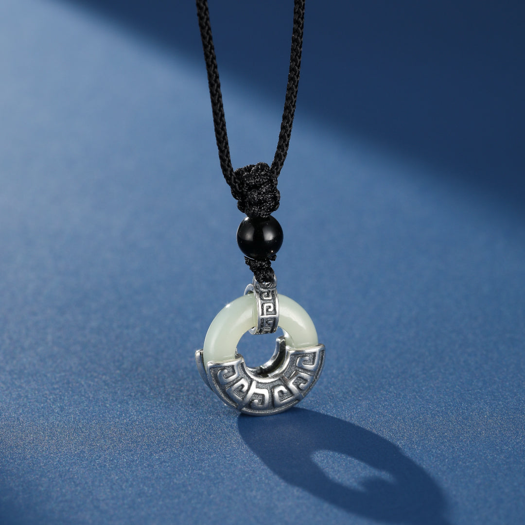 Collier homme avec pendentif circulaire en jade blanc et argent 925 orné de motifs anciens, monté sur cordon noir avec une perle d'obsidienne.