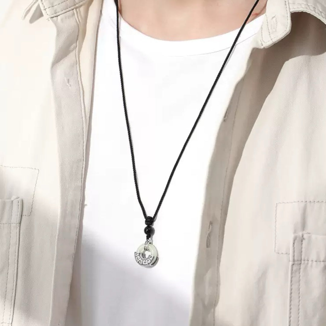 Collier pour homme en jade et obsidienne avec pendentif rond en argent 925, style Équilibre Ancien, porté sur une chemise beige et un t-shirt blanc.