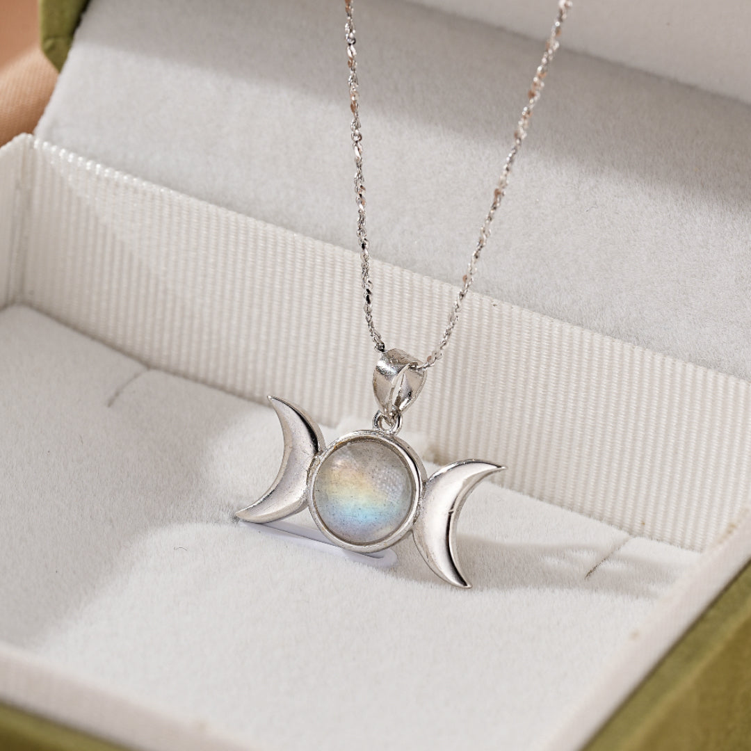 Collier en argent orné d'une pierre de labradorite centrale et de deux lunes en argent symbolisant la triple lune, présenté dans une boîte.