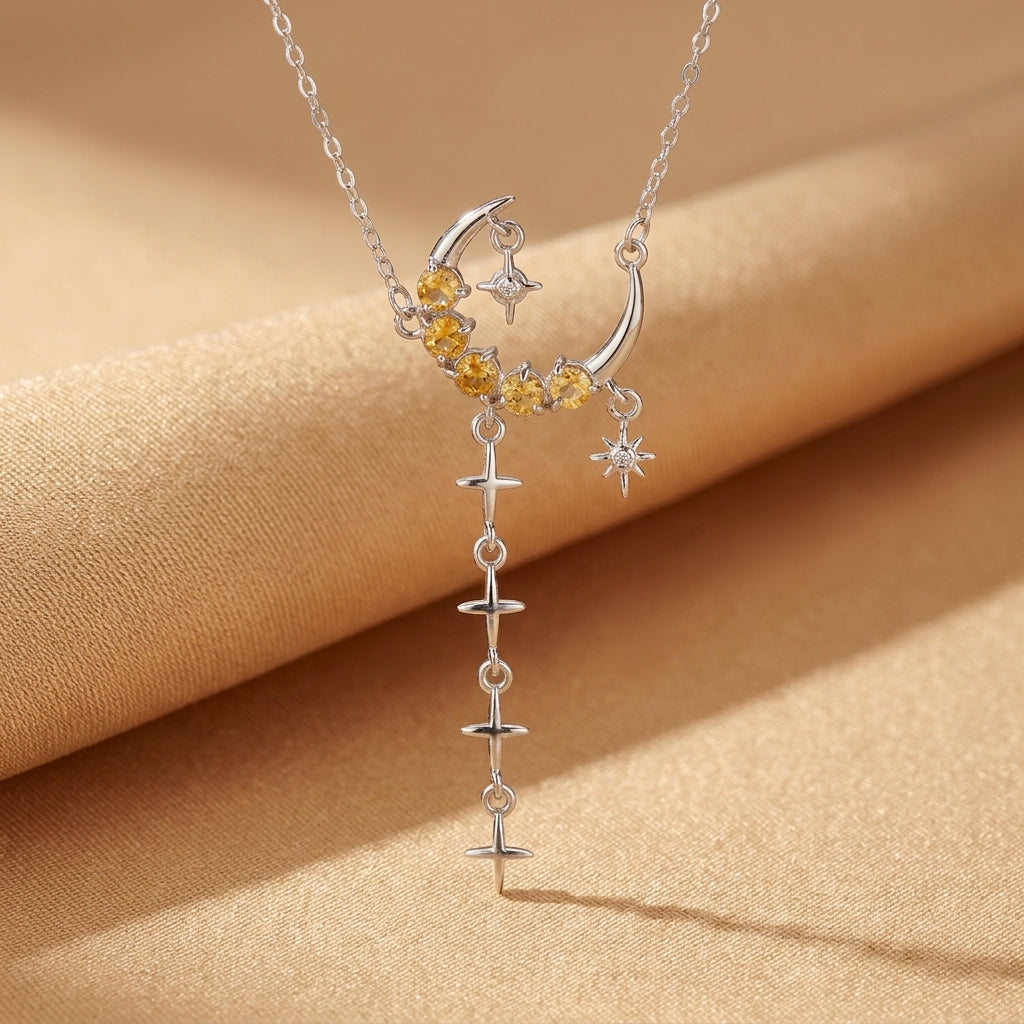 Collier argent en forme de croissant de lune orné de citrines et d'une étoile, avec une chaîne de petites étoiles suspendues.