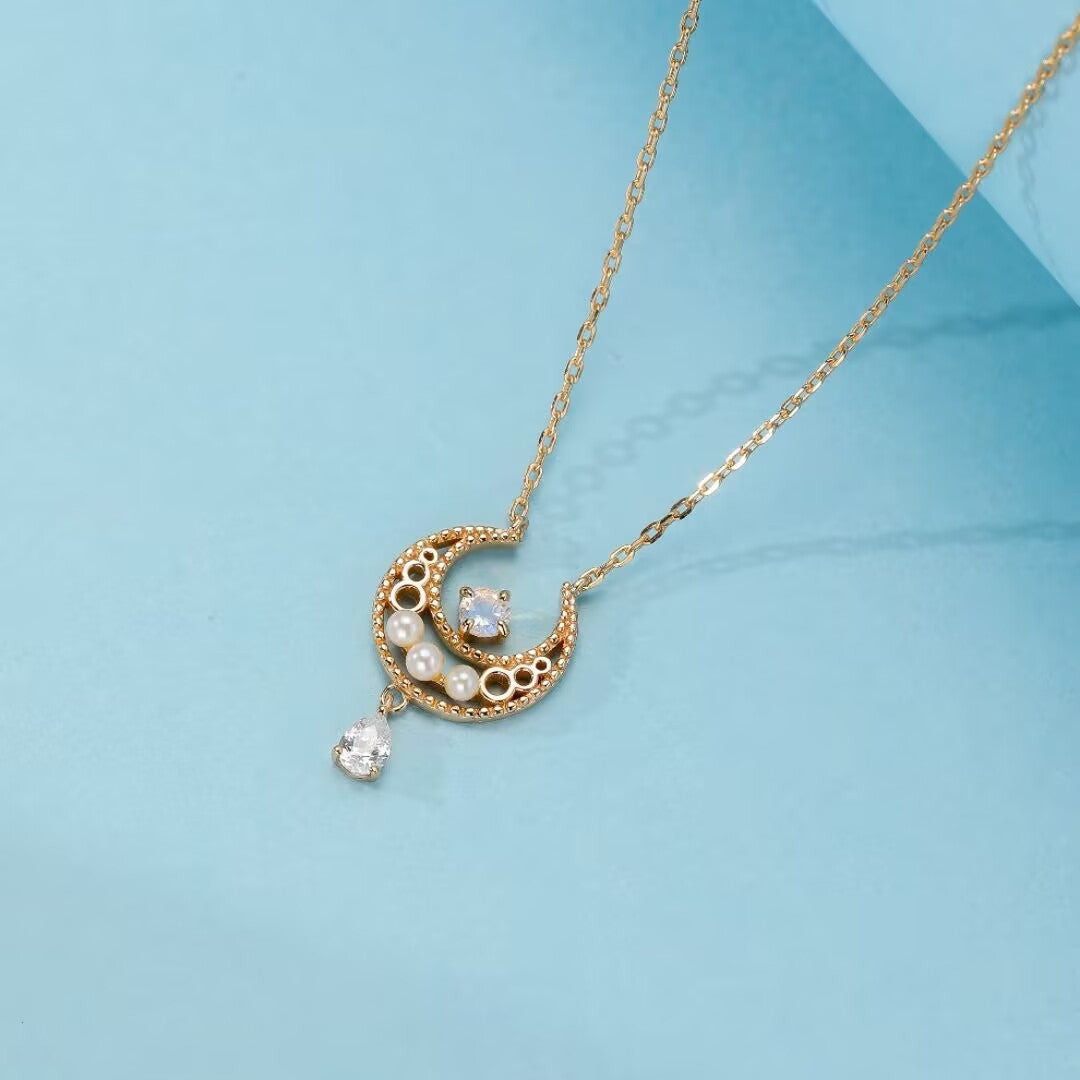 Collier en argent plaqué or en forme de croissant de lune orné de petites perles et d'une pierre de lune centrale, avec une goutte de zircone suspendue.