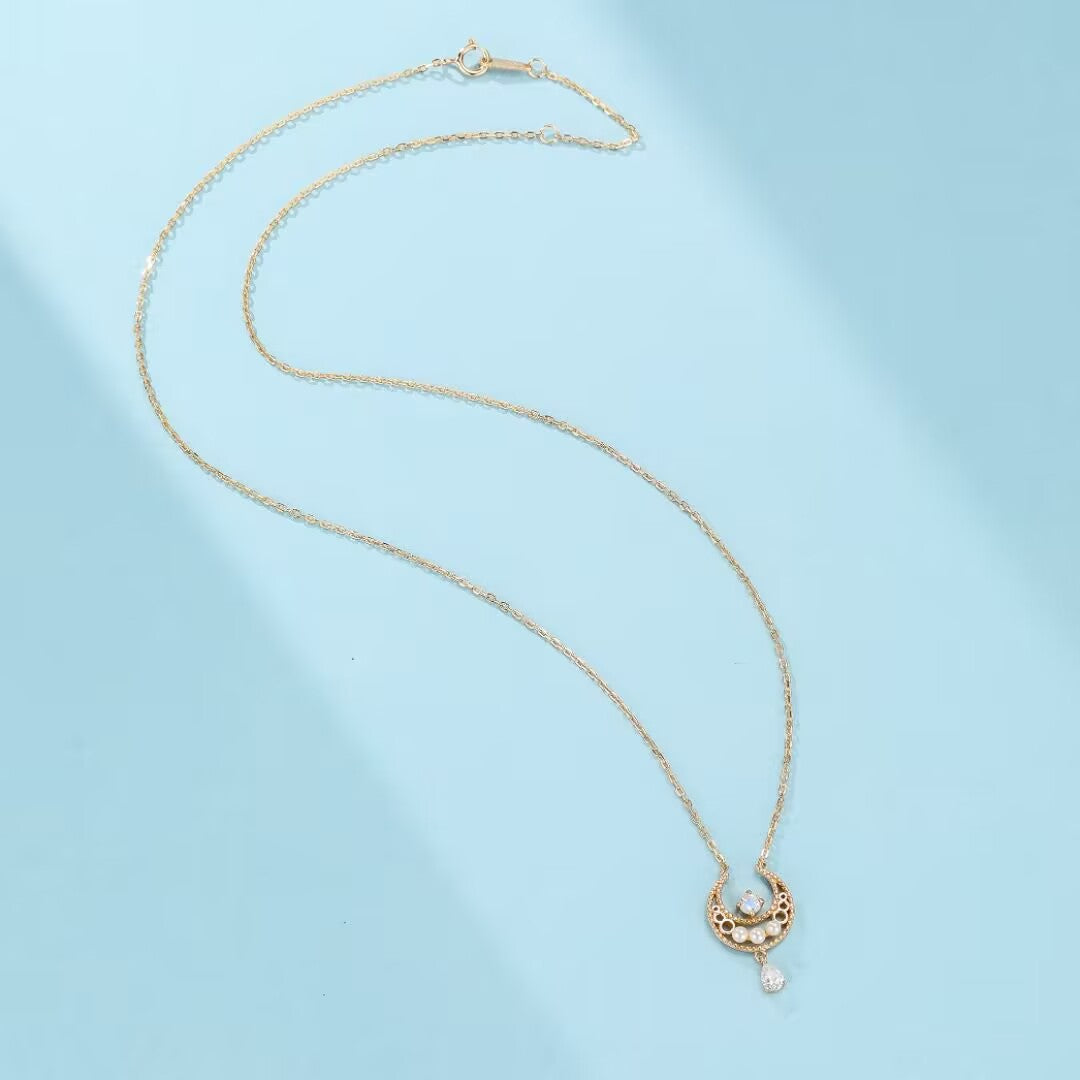 Collier lune en argent plaqué or avec une pierre de lune centrale et des détails ajourés, suspendu à une chaîne délicate.