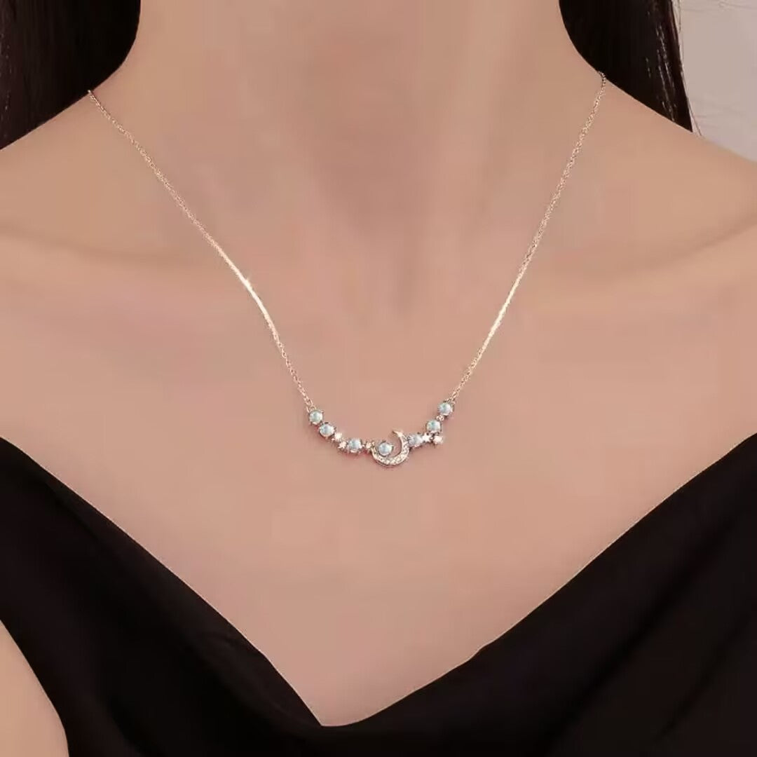 Collier "Souffle de Lune" en argent avec un pendentif croissant de lune orné de petites pierres bleues.