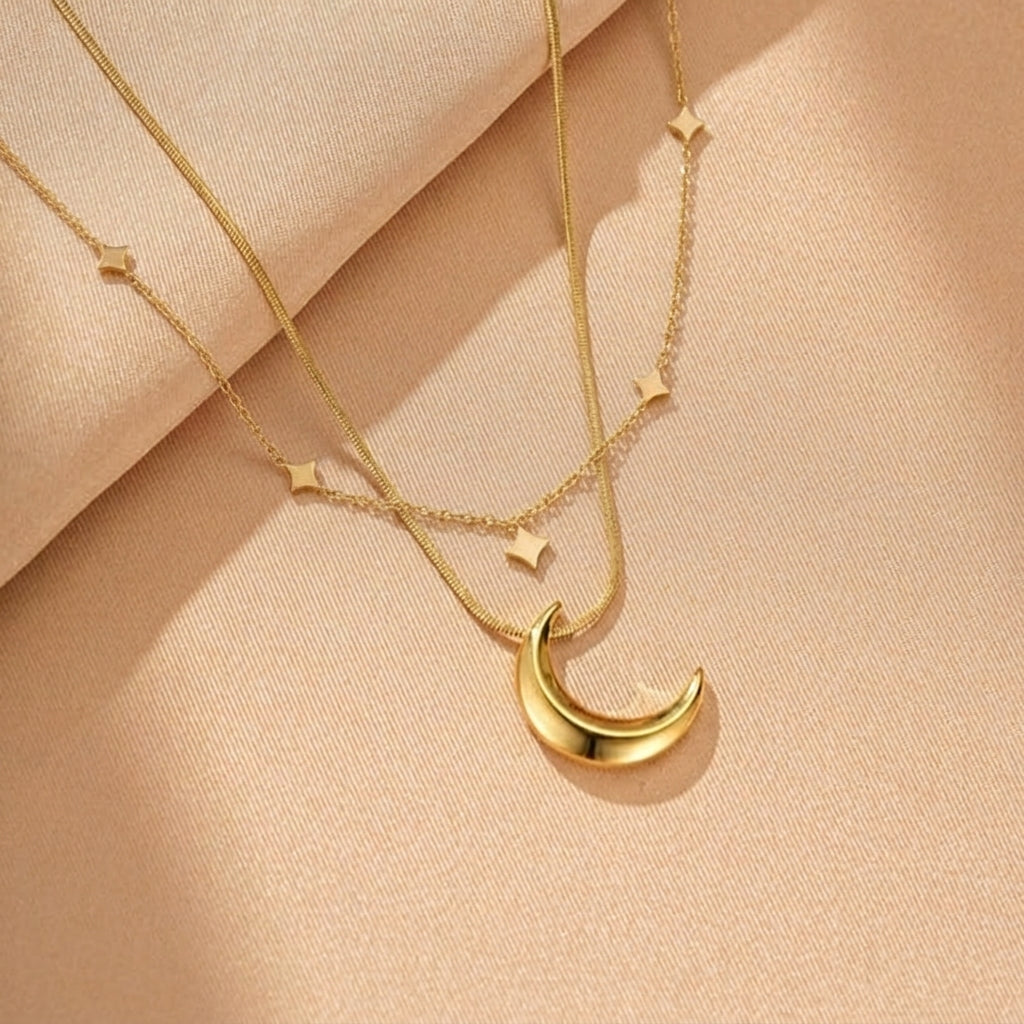 Collier doré à deux rangs orné d'une lune et d'étoiles carrées, sur fond de satin.