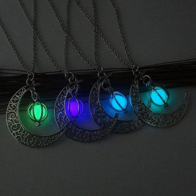 Plusieurs colliers avec un pendentif en forme de croissant de lune orné et une perle fluorescente dans différentes couleurs (vert, violet, bleu).