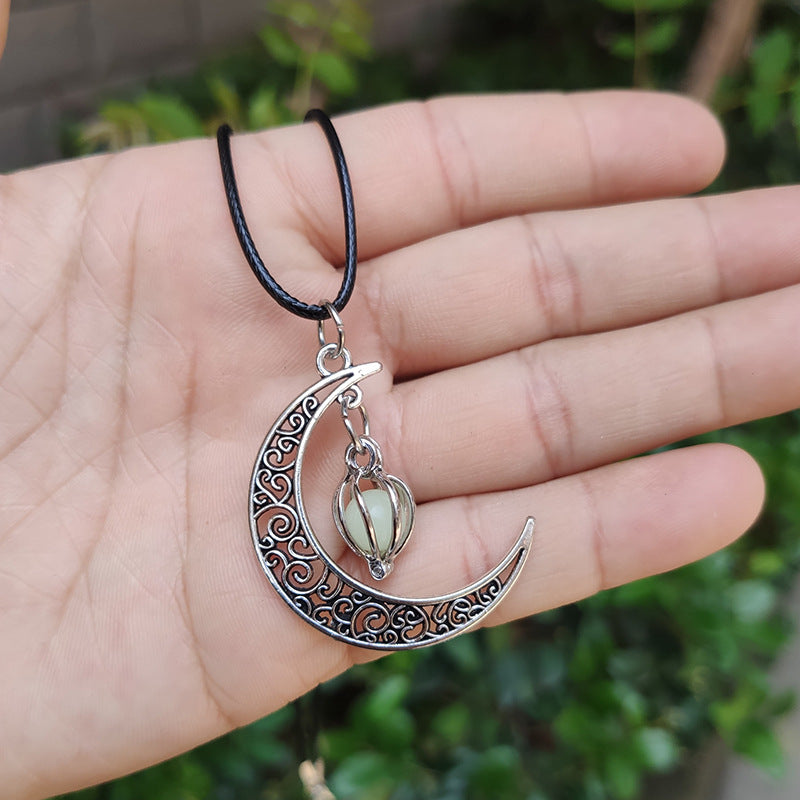 Collier "Rêve Etoilé" orné d'un pendentif lune argenté ajouré et d'une perle fluorescente lumineuse.