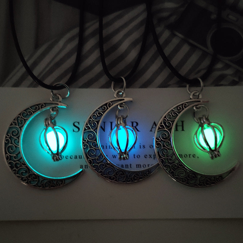Trois colliers avec un pendentif en forme de lune orné de motifs et une perle fluorescente lumineuse au centre, disponibles en bleu clair, bleu foncé et vert.