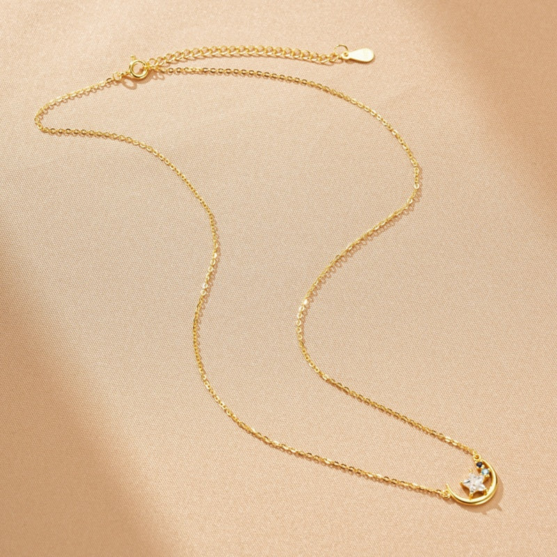 Collier en argent plaqué or 16K avec un croissant de lune orné d'une étoile blanche et de deux petites pierres bleues.