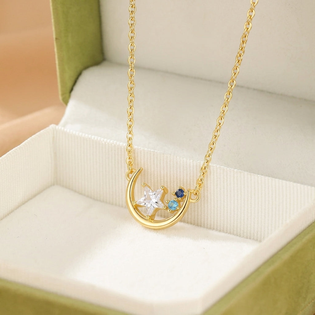 Collier en argent plaqué or 16K avec un croissant de lune orné d'une étoile blanche et de deux petites pierres bleues.
