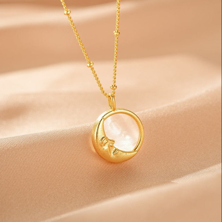 Collier Lune Nacre – Paix Nocturne, avec un pendentif rond en nacre blanche et une lune dorée sculptée sur le côté, monté sur une chaîne fine en or