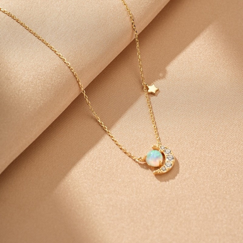 Collier en argent plaqué or avec un pendentif croissant de lune serti d'une opale et de petites pierres scintillantes, orné d'une petite étoile sur la chaîne.