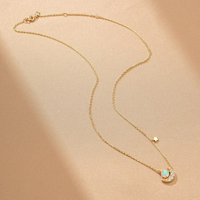 Collier en argent plaqué or avec un pendentif en forme de croissant de lune serti d'une opale et de petits diamants, orné d'une mini étoile scintillante.