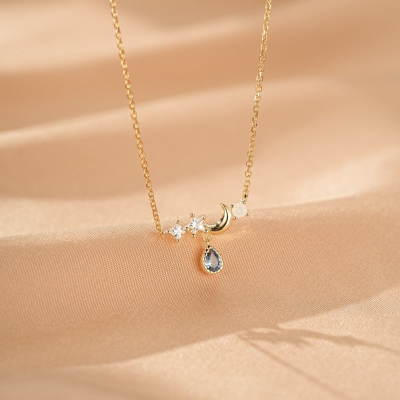 Collier fin en argent plaqué or 14k orné d'une lune, d'étoiles et d'une topaze bleue en forme de goutte.