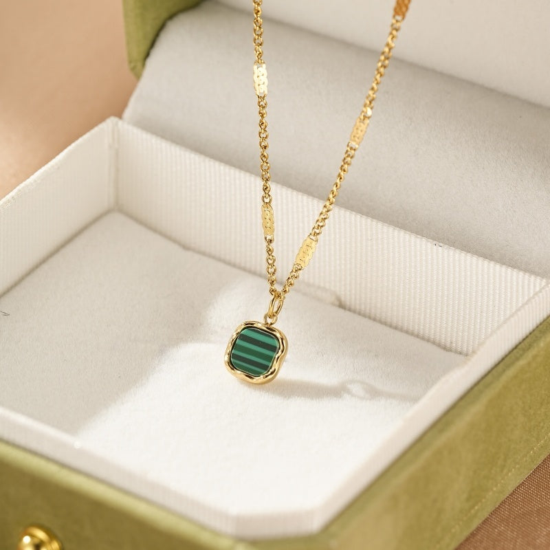 Collier plaqué or avec un pendentif carré en malachite verte à rayures, présenté dans une boîte bijou verte.
