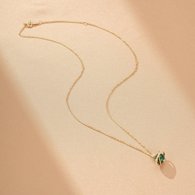 Collier Or Plaqué avec une sphère de Malachite verte et des détails scintillants, sur fond texturé.