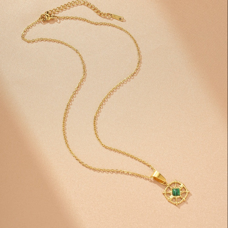 Collier en or avec un pendentif carré de malachite verte serti dans une monture dorée ornée de motifs complexes.
