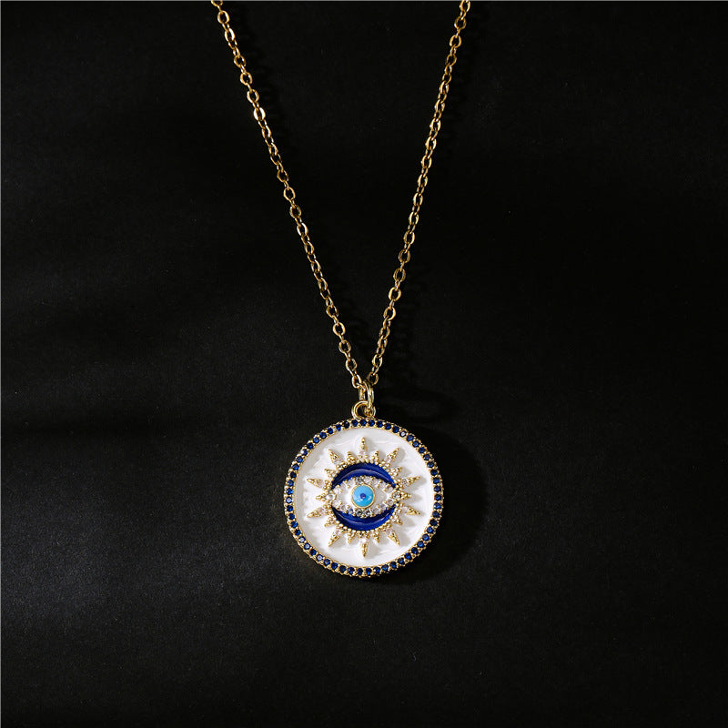 Collier rond avec un pendentif œil bleu entouré de zircons bleus et blancs sur une chaîne dorée.