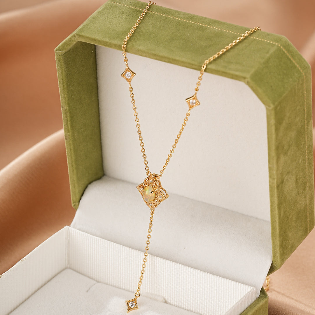 Collier en argent plaqué or 9 carats avec opale centrale et petits diamants incrustés, suspendu dans une boîte cadeau verte.