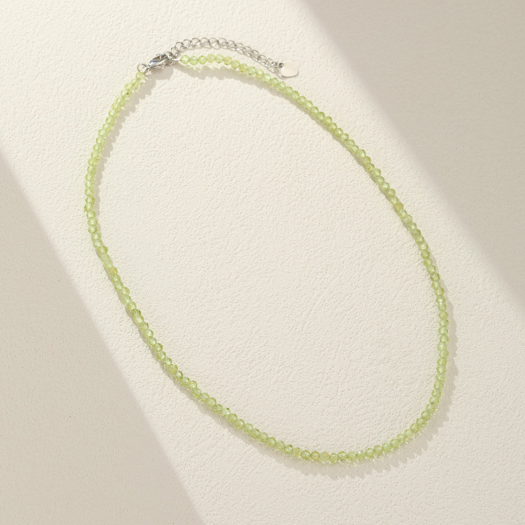 Collier fin avec de petites perles rondes vertes en péridot, doté d'une chaîne d'extension argentée.