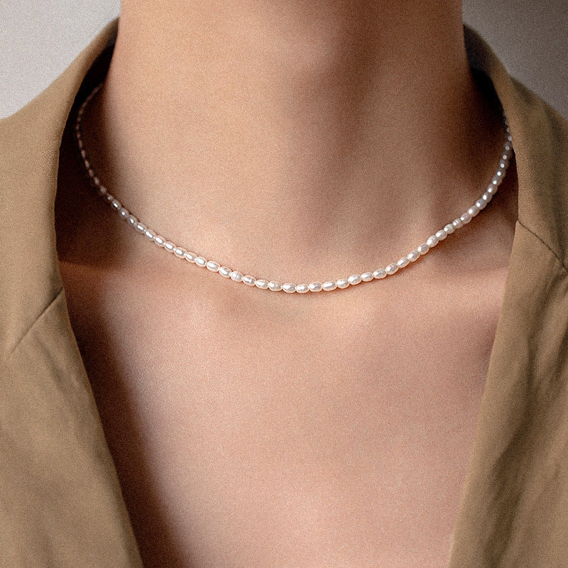 Collier ras de cou composé de petites perles blanches naturelles, monté sur une chaîne fine en argent plaqué or, porté par un mannequin.