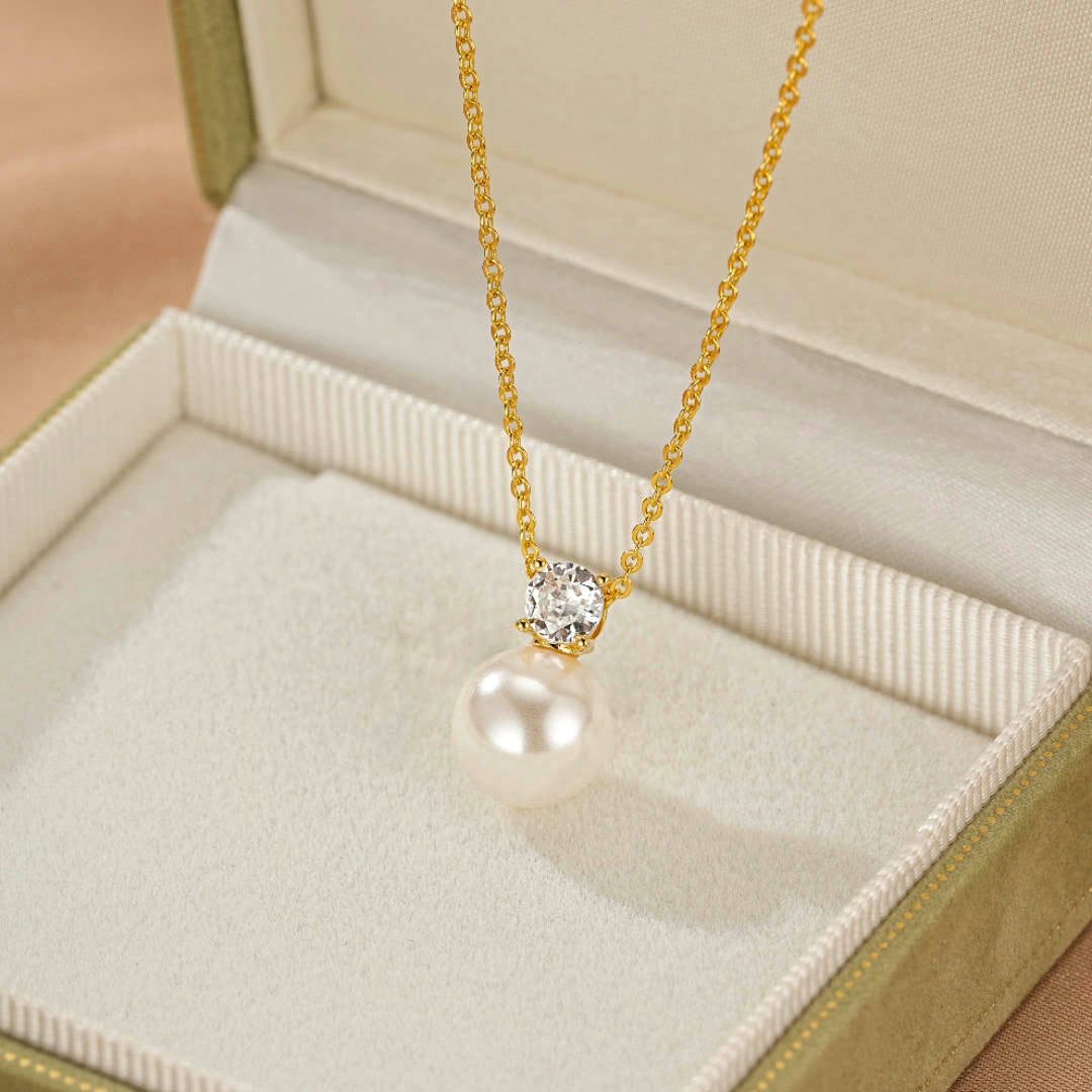 Collier en or avec une perle blanche et un zircon cubique, présenté dans un écrin.