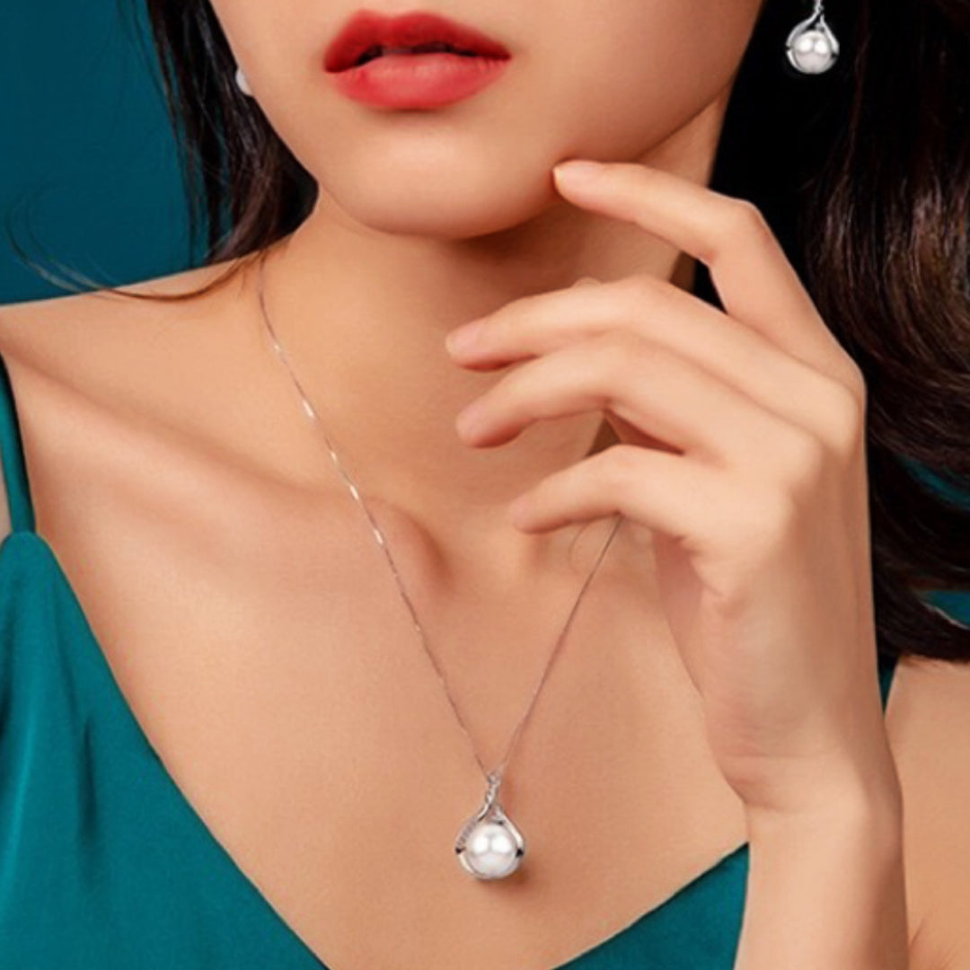 Collier en argent avec un pendentif en forme de goutte serti d'une perle blanche, porté par une femme.