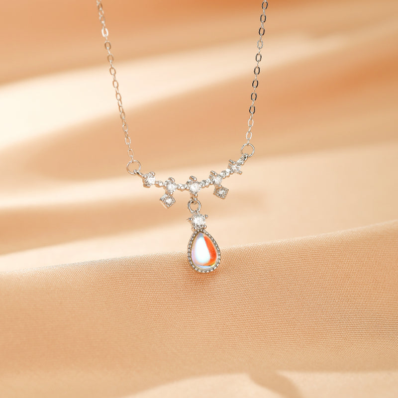 Collier en argent avec un pendentif goutte de pierre de lune aux reflets irisés, orné de petites zircons cubiques sertis sur une chaîne délicate.