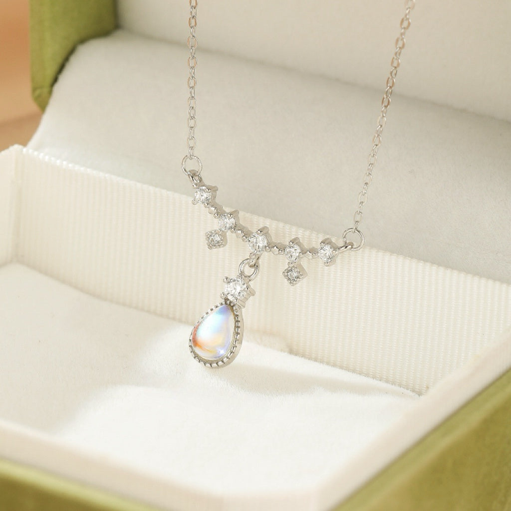 Collier pendentif goutte en pierre de lune irisée, monté sur une chaîne en argent ornée de cristaux.