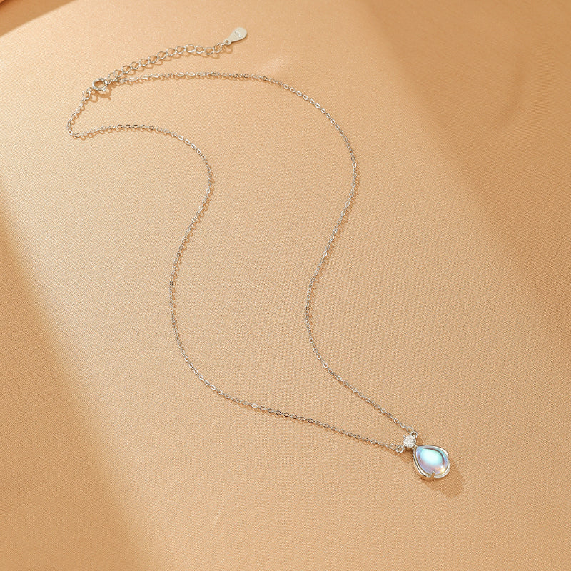 Collier en argent sterling avec une pierre de lune bleu pâle en forme de larme et un petit diamant scintillant, suspendu à une fine chaîne en argent.
