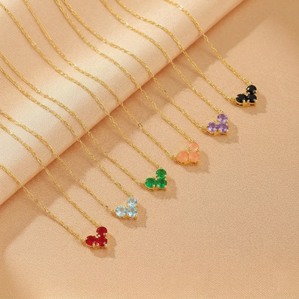 Collection de colliers "Arc-en-ciel Précieux" en argent plaqué or, chacun orné de pierres de naissance colorées disposées en forme de cœur : rouge, bleu clair, vert émeraude, rose pêche, améthyste et onyx noir.