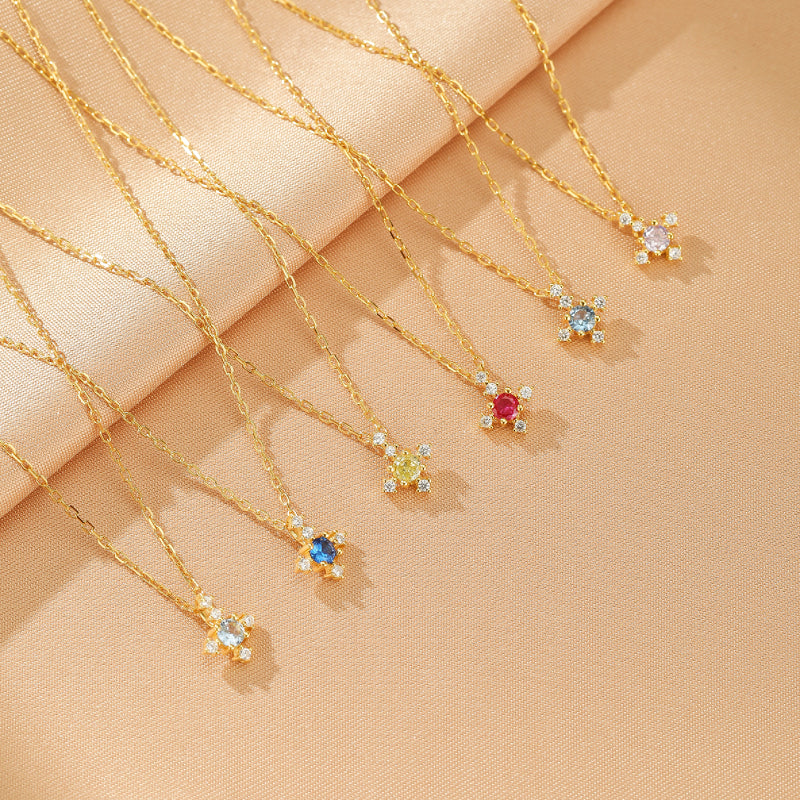 Collection de colliers plaqué or avec pendentifs en forme de fleur sertis de pierres de naissance colorées et de diamants scintillants.