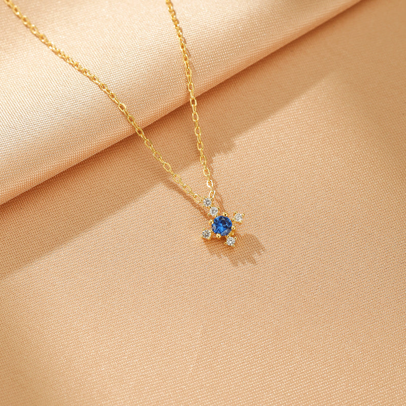 Collier Azur Infini en argent plaqué or avec une pierre bleue centrale et des petites pierres blanches.