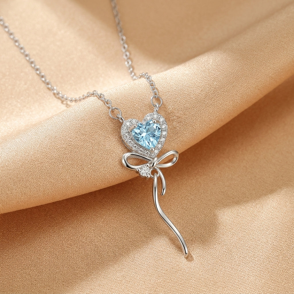 Collier Cœur Enchanté en argent plaqué or 18k avec pierre bleue centrale et nœud orné de petits zircons