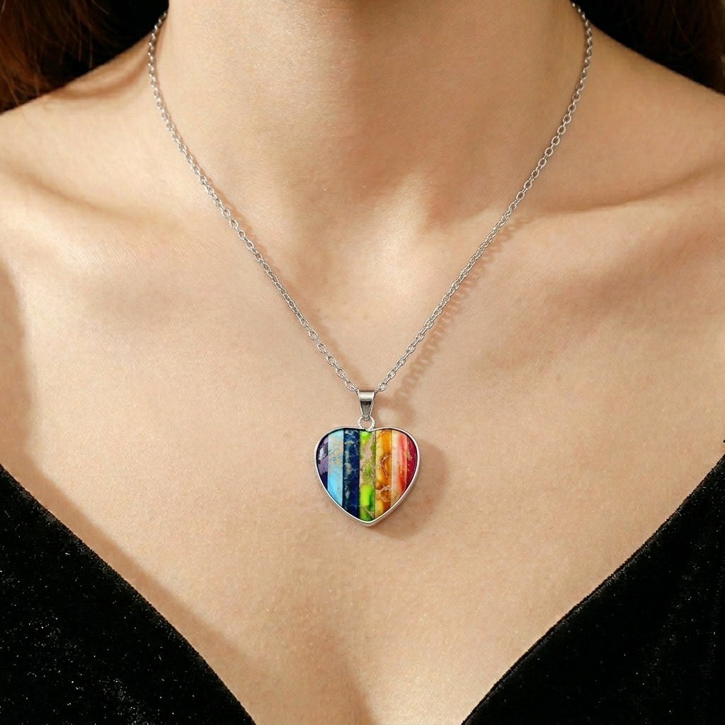 Collier en argent avec pendentif en forme de cœur multicolore rayé, porté par une femme.