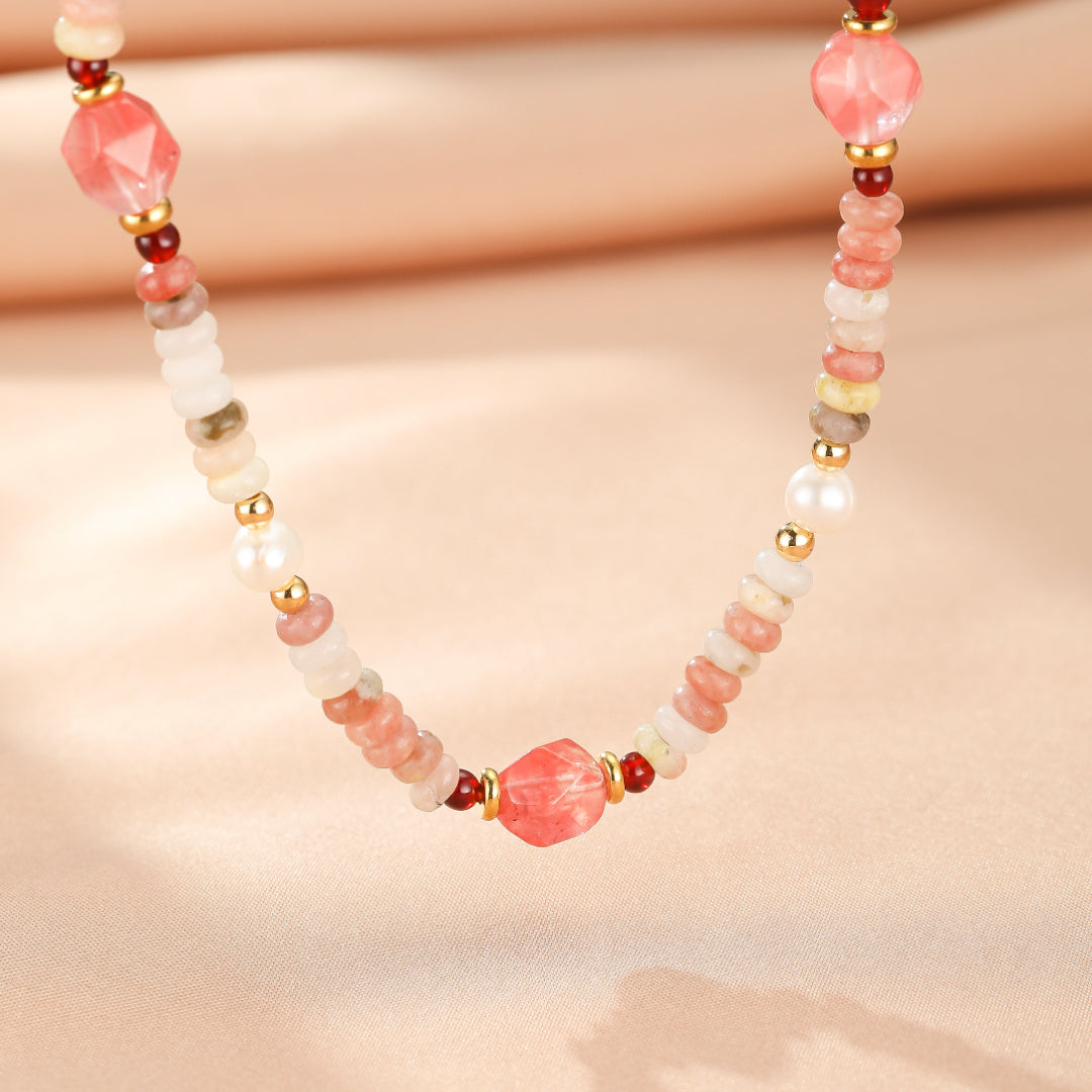 Collier artisanal en rhodonite rose, perles de culture et petites perles dorées, orné d'une pierre centrale facettée rose et de perles rouges. Style bohème chic.