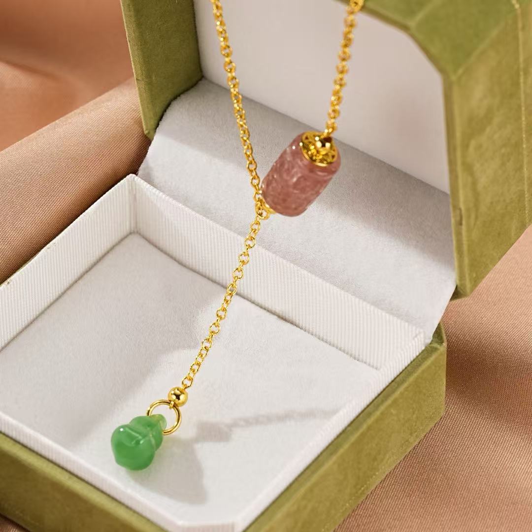 Collier en or jaune avec pendentif en forme de gourde en jade vert et une tourmaline rose sculptée, présenté dans une boîte cadeau verte.