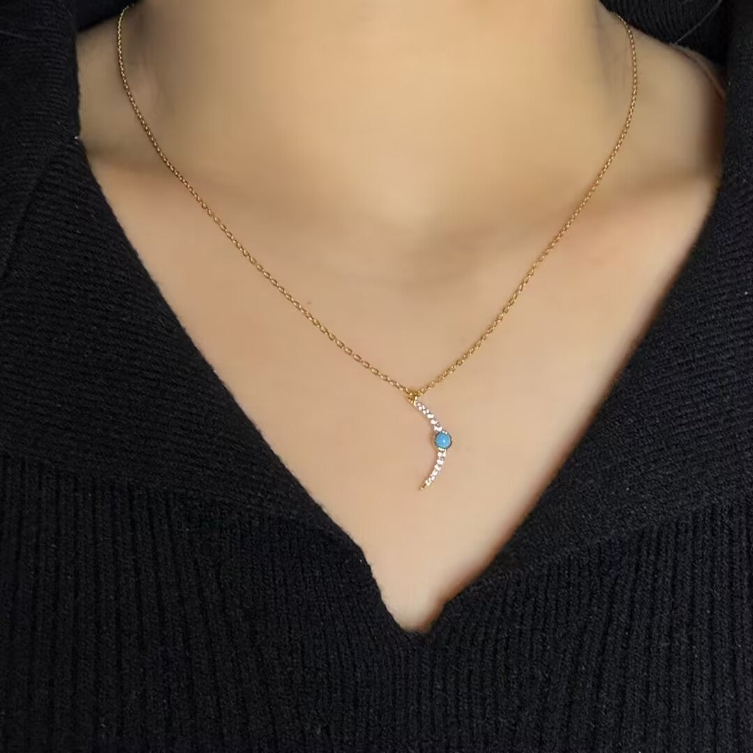 Collier fin en argent avec un pendentif en forme de croissant de lune orné d'une petite turquoise bleue et de zirconiums scintillants