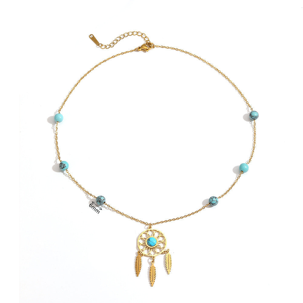 Collier doré avec un pendentif attrape-rêves serti d'une turquoise centrale et orné de trois plumes dorées, agrémenté de perles turquoise de 6mm réparties sur la chaîne.