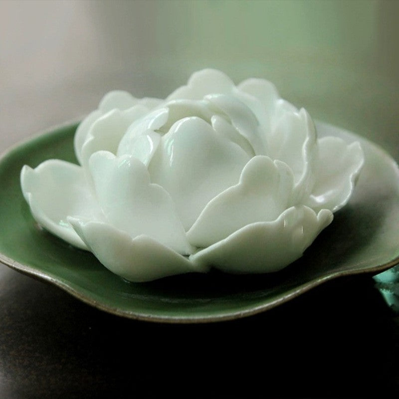 Encensoir en forme de fleur de pivoine blanche en céramique, posé sur une soucoupe verte