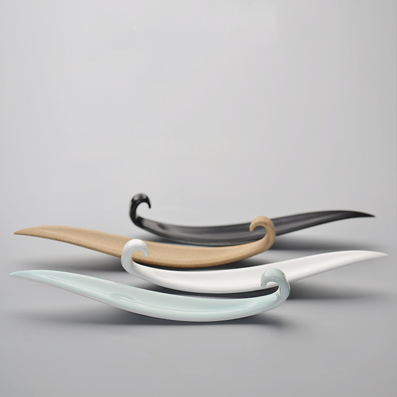 Quatre encensoirs en forme de vague en céramique dans différentes couleurs : bleu pâle, blanc, beige et noir, posés sur un fond gris.