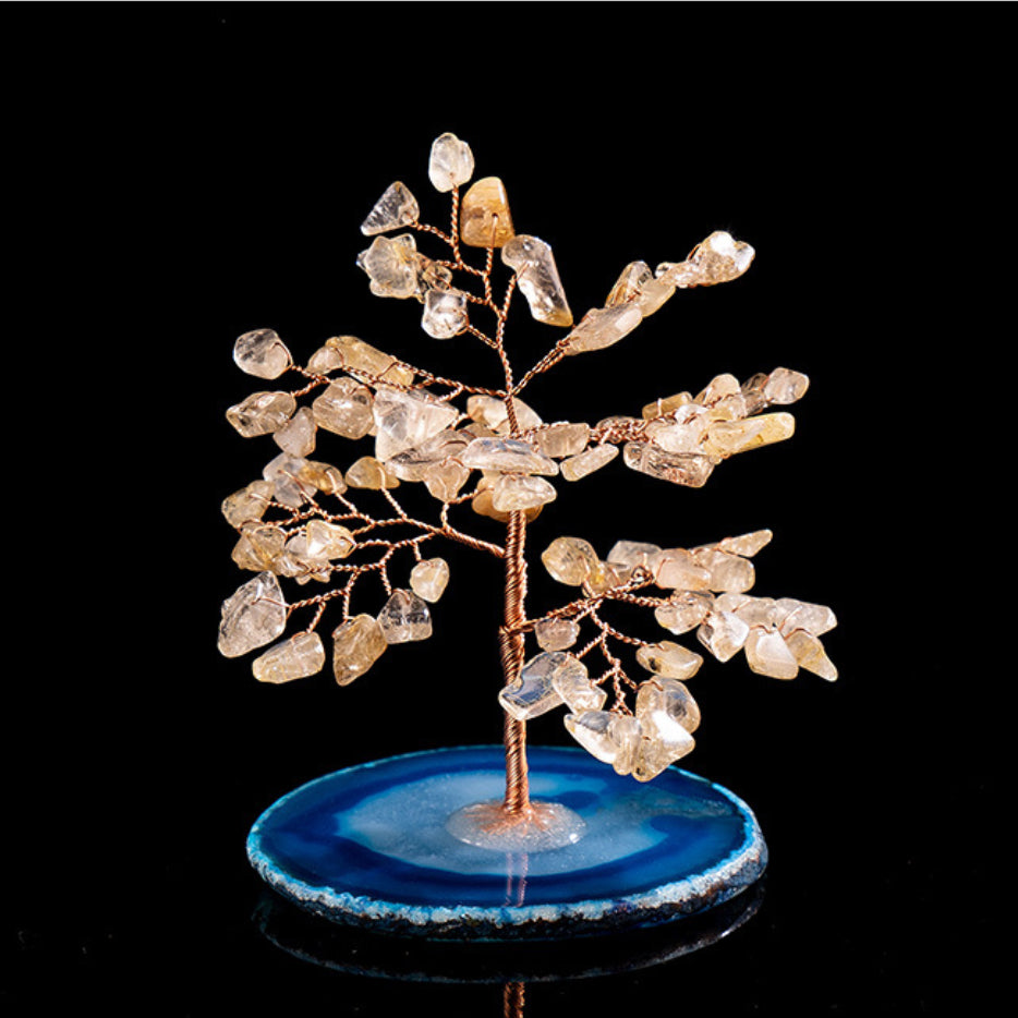 Arbre de vie décoratif fait de pierres de quartz rutile et d'une base en agate bleue, sur fond noir.
