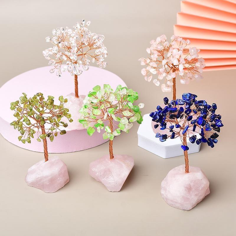 Cinq arbres décoratifs en pierres naturelles sur des socles en quartz rose. L'un a des feuilles bleues, deux ont des feuilles vertes, un a des feuilles roses pâles et un a des feuilles blanches.