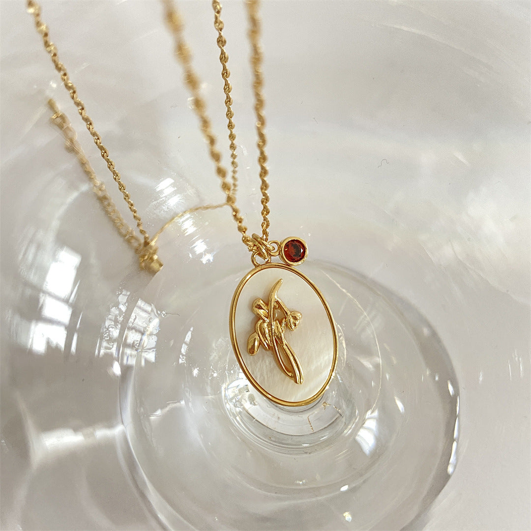 Pendentif or blanc avec nénuphar sculpté et grenat, symbolisant le mois de juillet.